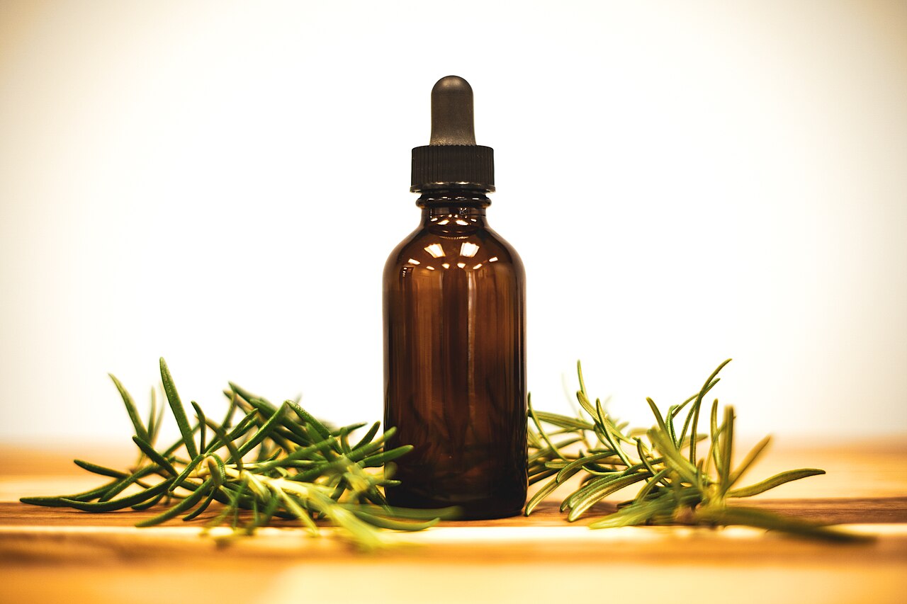 Rosemary Oil in a bottle and rosemary herb